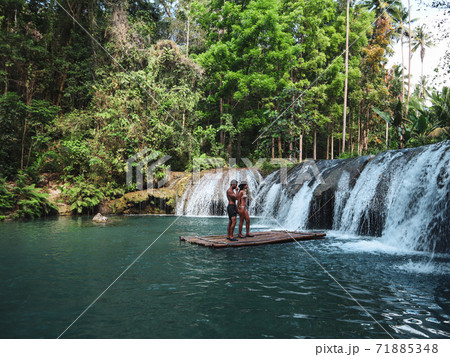 Lovely travel couple at the tropical wild nature adventure on the bamboo raft in Cambugahay Waterfalls in Siquijor Island, Philippines  71885348