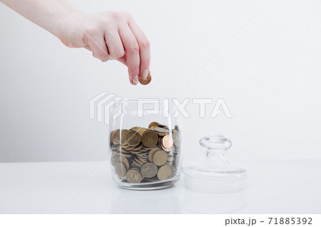 Coins in a glass bank and female's hand. Deposit concept Coins in a glass bank and female's hand. Deposit concept 71885392