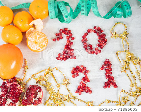 2021 number made from pomegranate seeds, fruits and tape measure on the table  71886005