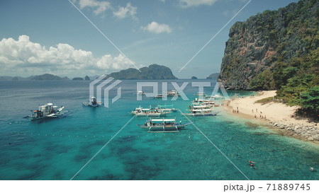 Aerial view of paradise vacation on passenger boats. Tourists rest at sand beach of Palawan island Aerial view of paradise vacation on passenger boats. Tourists rest at sand beach of Palawan island 71889745