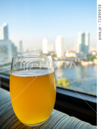Glass of lager beer on edge of window with Bangkok skyscraper buildings cityscape view in background 71890658