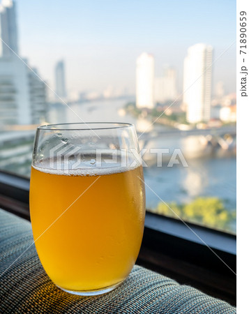 Glass of lager beer on edge of window with Bangkok skyscraper buildings cityscape view in background 71890659