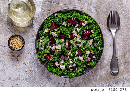 Healthy raw kale and beetroot salad with feta cheese and pine nut. 71894278