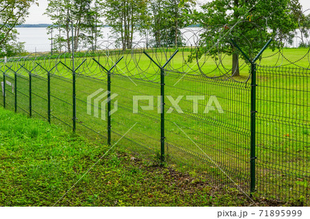 a metal fence of a military object with barbed wire a metal fence of a military object with barbed wire 71895999