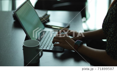 Female hand typing on tablet keyboard on worktable in office room 71899507