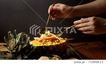 Female hands with cutlery eating Pineapple Fried Rice  (Kao Pad Sapparod) 71899613