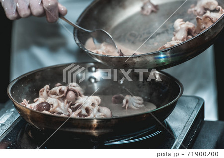 The chef cooks the small octopus on a metal frying pan 71900200