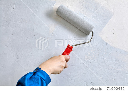 Handyman uses paints and paint roller for painting wall. Handyman uses paints and paint roller for painting wall. 71900452