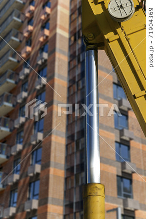 Part of a construction machine (excavator or crane) with multi-storey building under construction (new residential complex) on the background, Moscow, Russia 71904369