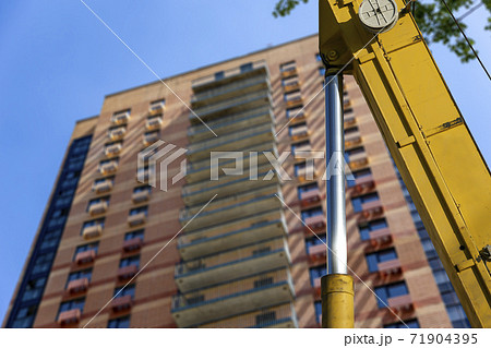 Part of a construction machine (excavator or crane) with multi-storey building under construction (new residential complex) on the background, Moscow, Russia Part of a construction machine (excavator or crane) with multi-storey building under construction (new residential complex) on the background, Moscow, Russia 71904395