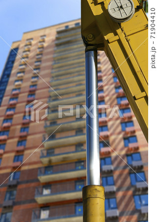 Part of a construction machine (excavator or crane) with multi-storey building under construction (new residential complex) on the background, Moscow, Russia Part of a construction machine (excavator or crane) with multi-storey building under construction (new residential complex) on the background, Moscow, Russia 71904410