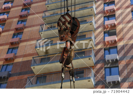 Construction crane hook with multi-storey building under construction (new residential complex) on the background. Construction site upon renovation program in Cheryomushki district, Moscow, Russia 71904442