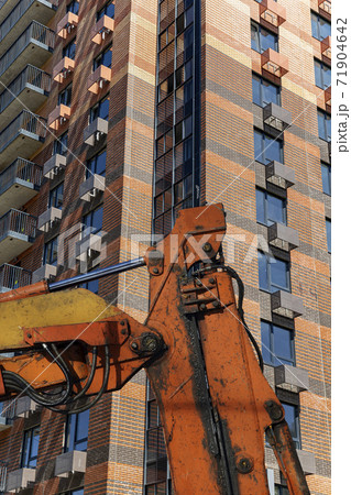 Part of a construction machine  with multi-storey building under construction (new residential complex) on the background. 71904642
