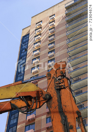 Part of a construction machine with multi-storey building under construction (new residential complex) on the background. Part of a construction machine with multi-storey building under construction (new residential complex) on the background. 71904674