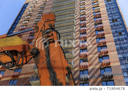 Part of a construction machine  with multi-storey building under construction (new residential complex) on the background. 71904678
