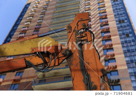 Part of a construction machine with multi-storey building under construction (new residential complex) on the background. Part of a construction machine with multi-storey building under construction (new residential complex) on the background. 71904681
