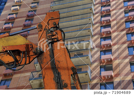 Part of a construction machine with multi-storey building under construction (new residential complex) on the background. Part of a construction machine with multi-storey building under construction (new residential complex) on the background. 71904689