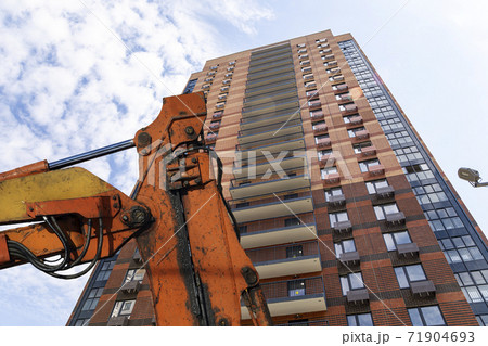 Part of a construction machine  with multi-storey building under construction (new residential complex) on the background. 71904693