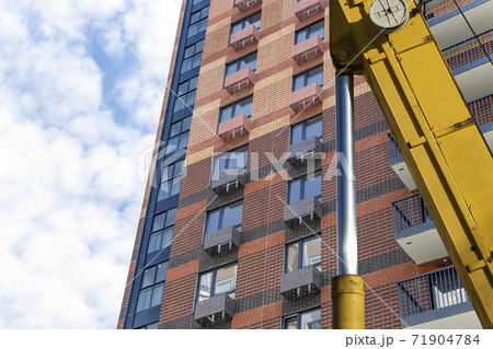 Part of a construction machine (excavator or crane) with multi-storey building under construction (new residential complex) on the background, Moscow, Russia Part of a construction machine (excavator or crane) with multi-storey building under construction (new residential complex) on the background, Moscow, Russia 71904784