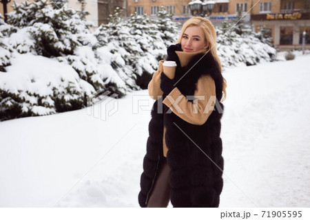 Portrait of european style fashionable woman drinking coffee in winter park. Portrait of european style fashionable woman drinking coffee in winter park. 71905595