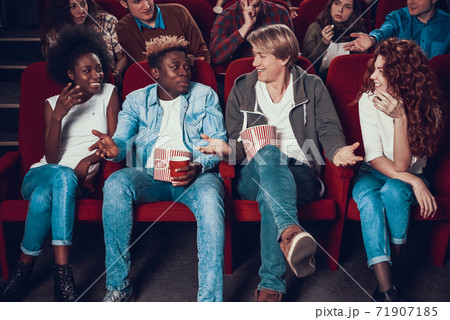 Two friends sit in front row at cinema and talk.  71907185