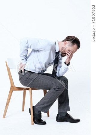 A man sits on a chair and feels back pain. A man sits on a chair and feels back pain. 71907952