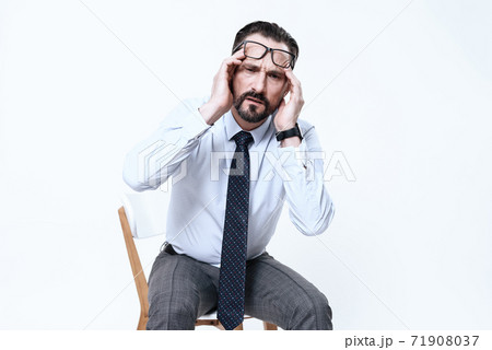 A man sits on a chair and has a strong migraine. A man sits on a chair and has a strong migraine. 71908037