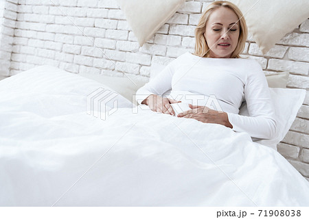 Woman is lying in bed and holding on to pms belly. Woman is lying in bed and holding on to pms belly. 71908038