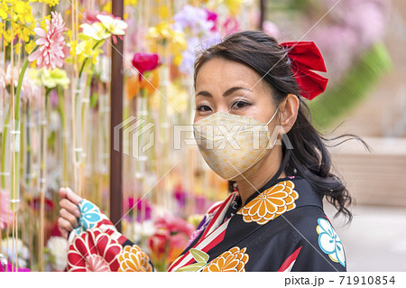 東京 日比谷 東京ミッドタウン日比谷で花の壁の前に立つマスクを付けた花柄のハイカラの袴を着た女性の写真素材