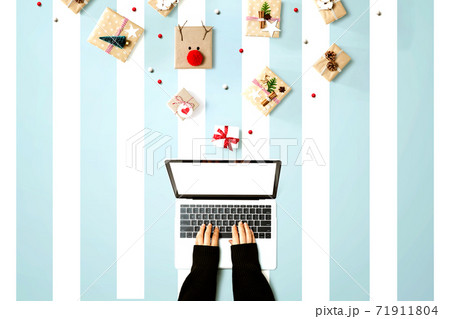 Person using a laptop computer with Christmas gift boxes 71911804