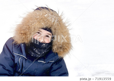 A child in a blue a fur hood, closeup of brown smiling eyes. Looks out with ruddy cheeks, frost on a snowy winter day. 71913559
