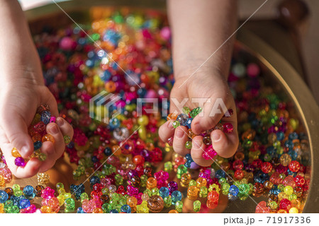 A girl's hand holds colored heart shaped beads 71917336