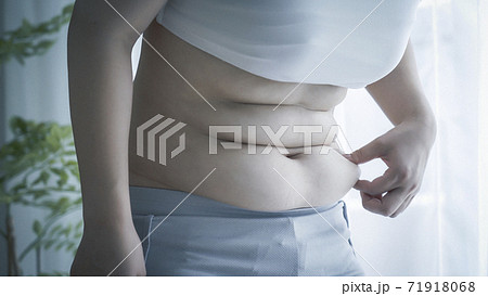 お腹の肉を摘む女性の写真素材