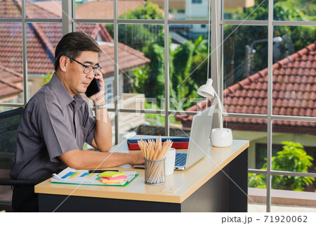 senior businessman sitting on desk office he using his mobile phone 71920062