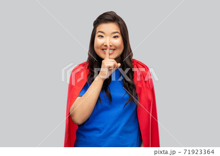 asian woman in superhero cape making hush gesture 71923364