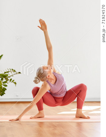 young woman doing garland pose at yoga studio 71924570