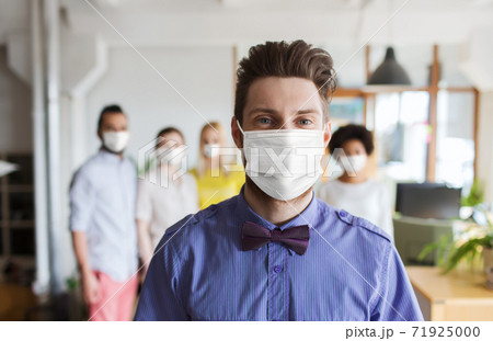 young man in mask over creative team at office young man in mask over creative team at office 71925000