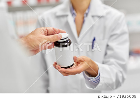 pharmacist and customer with medicine at pharmacy 71925009