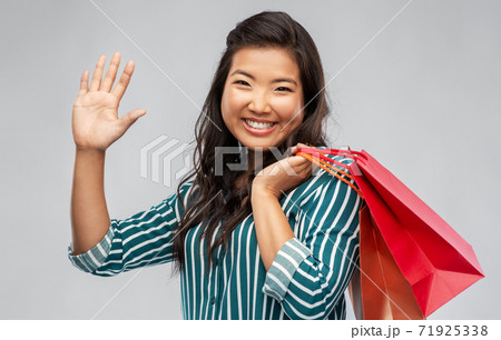 happy asian woman with shopping bags waving hand happy asian woman with shopping bags waving hand 71925338