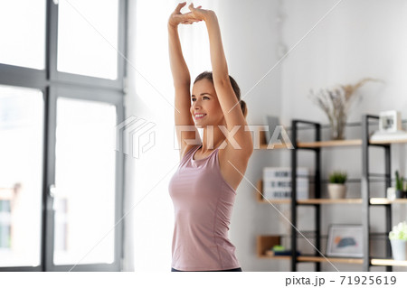 smiling young woman stretching arms at home smiling young woman stretching arms at home 71925619