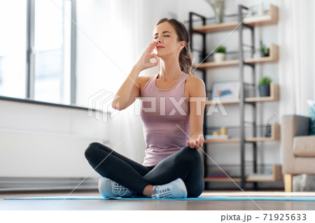 woman doing yoga in lotus pose at home woman doing yoga in lotus pose at home 71925633