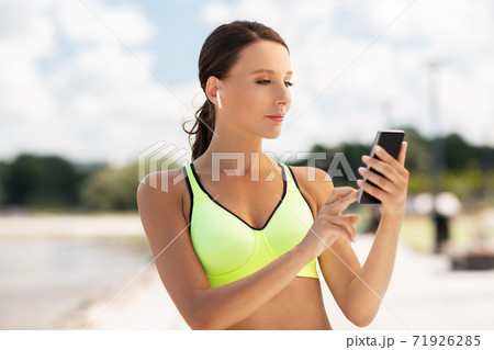 woman with earphones and smartphone doing sports 71926285