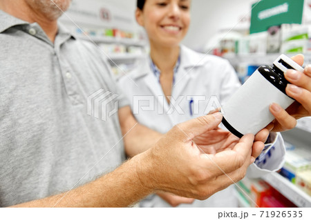 pharmacist and old man with medicine at pharmacy 71926535