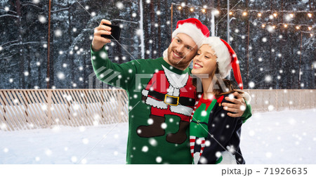 happy couple in christmas sweaters taking selfie happy couple in christmas sweaters taking selfie 71926635