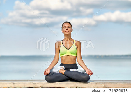 young woman meditating in lotus pose at seaside young woman meditating in lotus pose at seaside 71926853