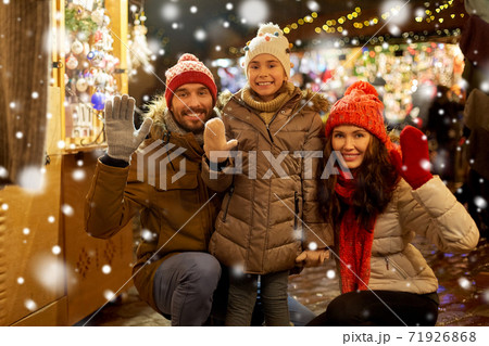 happy family waving hands at christmas market 71926868