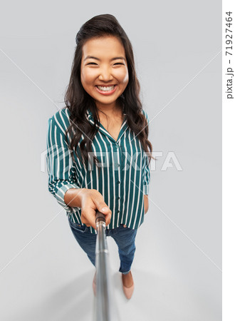 happy asian woman taking picture with selfie stick happy asian woman taking picture with selfie stick 71927464