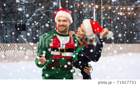 happy couple in christmas sweaters taking selfie happy couple in christmas sweaters taking selfie 71927731