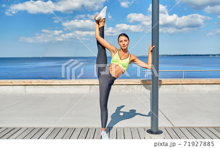 woman doing sports and stretching leg at seaside 71927885