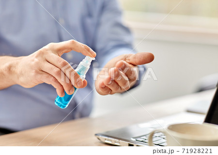 man using hand sanitizer at home office man using hand sanitizer at home office 71928221